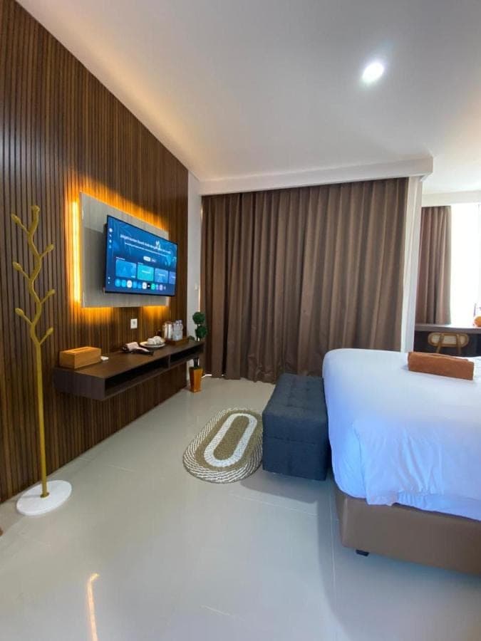 a bedroom with a bed and a tv on a wall at Queens Villa in Seminyak
