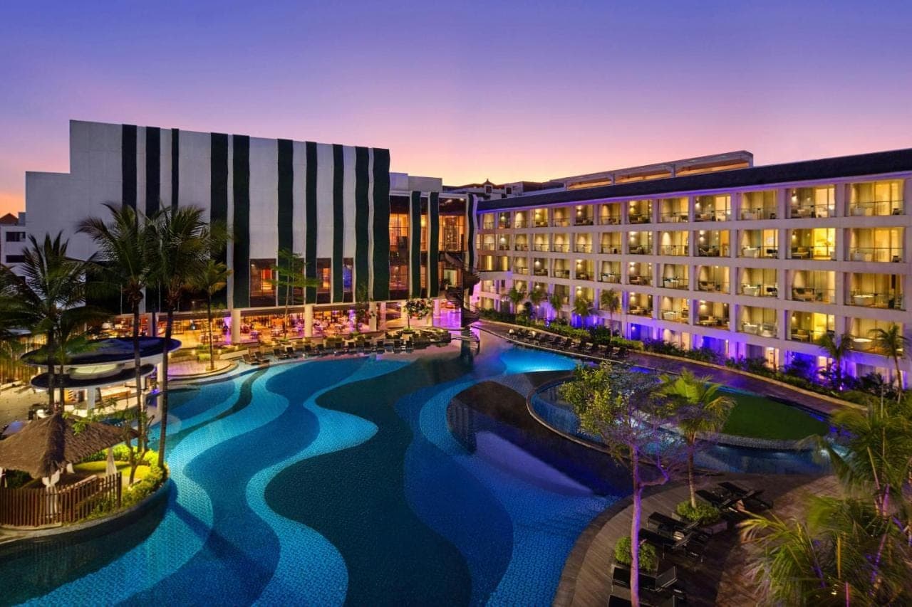 a hotel with a pool in front of a building at The Stones Hotel - Legian Bali in Kuta