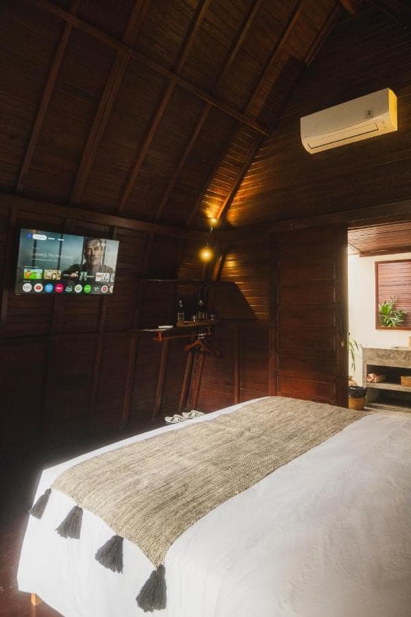 a bedroom with a bed and a tv on the wall at Savanna Ubud in Ubud