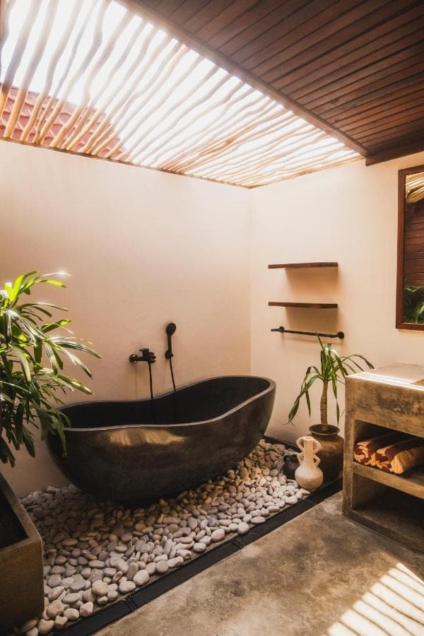 a bathroom with a large bath tub on rocks at Savanna Ubud in Ubud