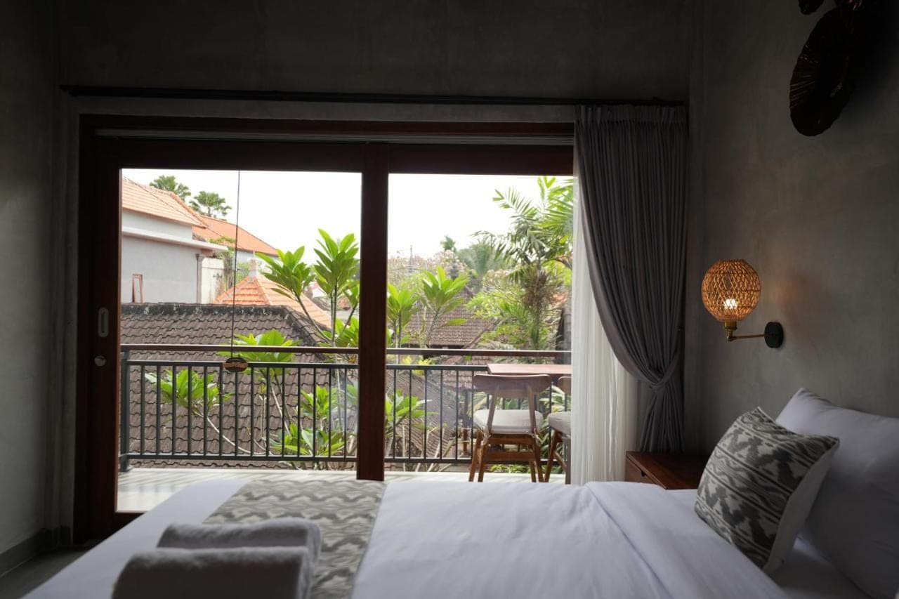 a bedroom with a bed and a view of a balcony at Nuna House Ubud in Ubud