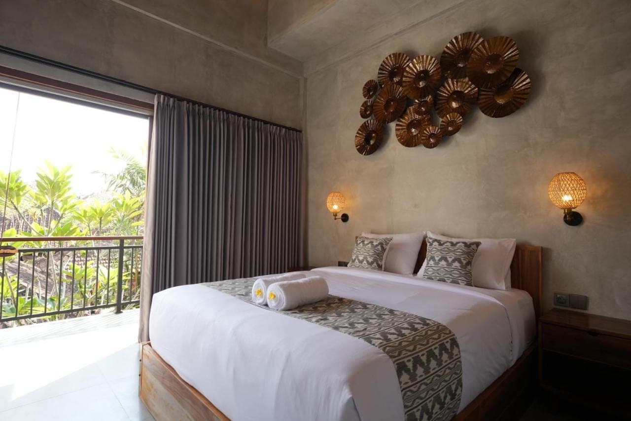 a bedroom with a large bed and a balcony at Nuna House Ubud in Ubud