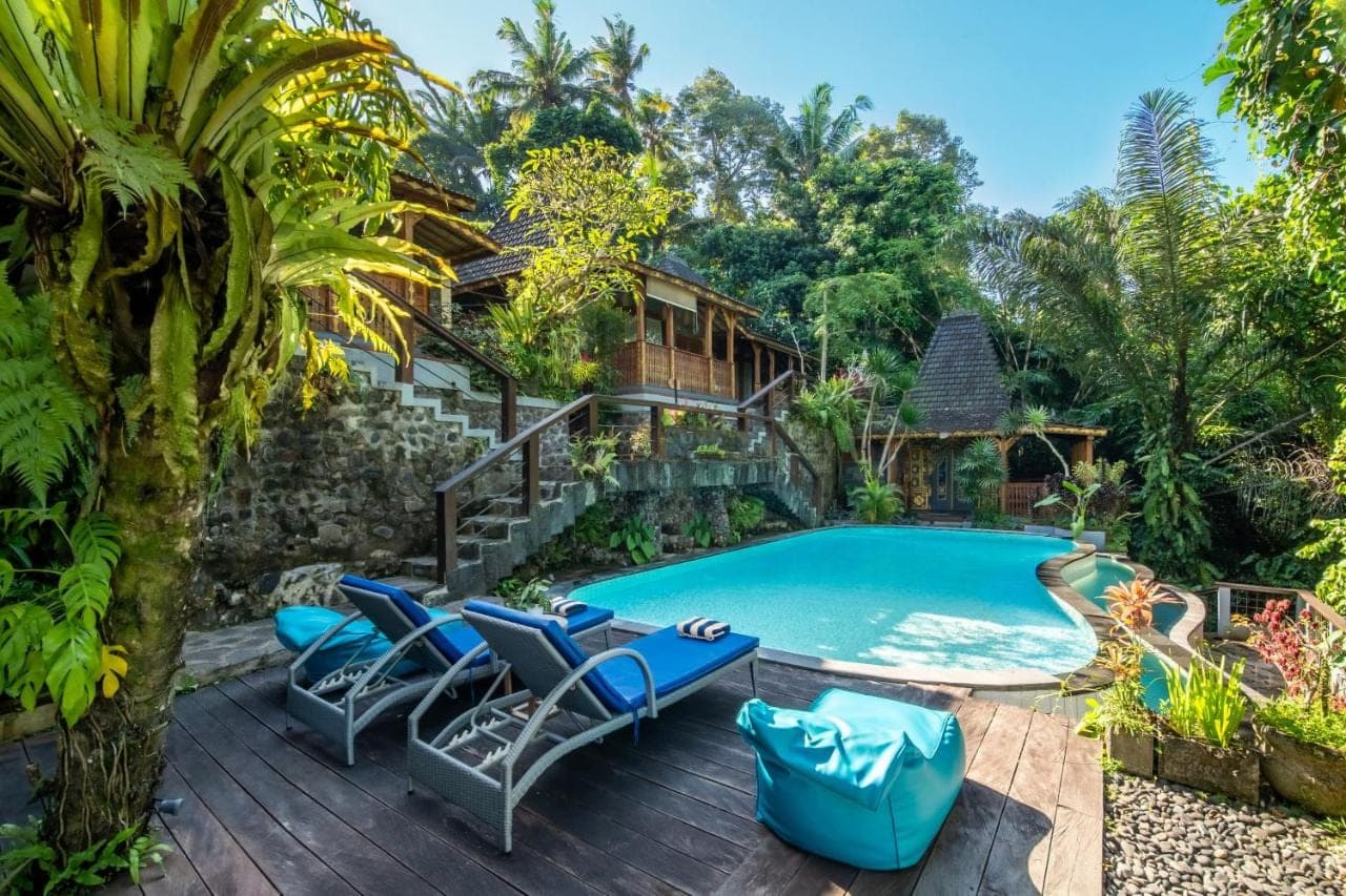 a swimming pool with chairs and a house at Parvati Retreat Villas in Ubud