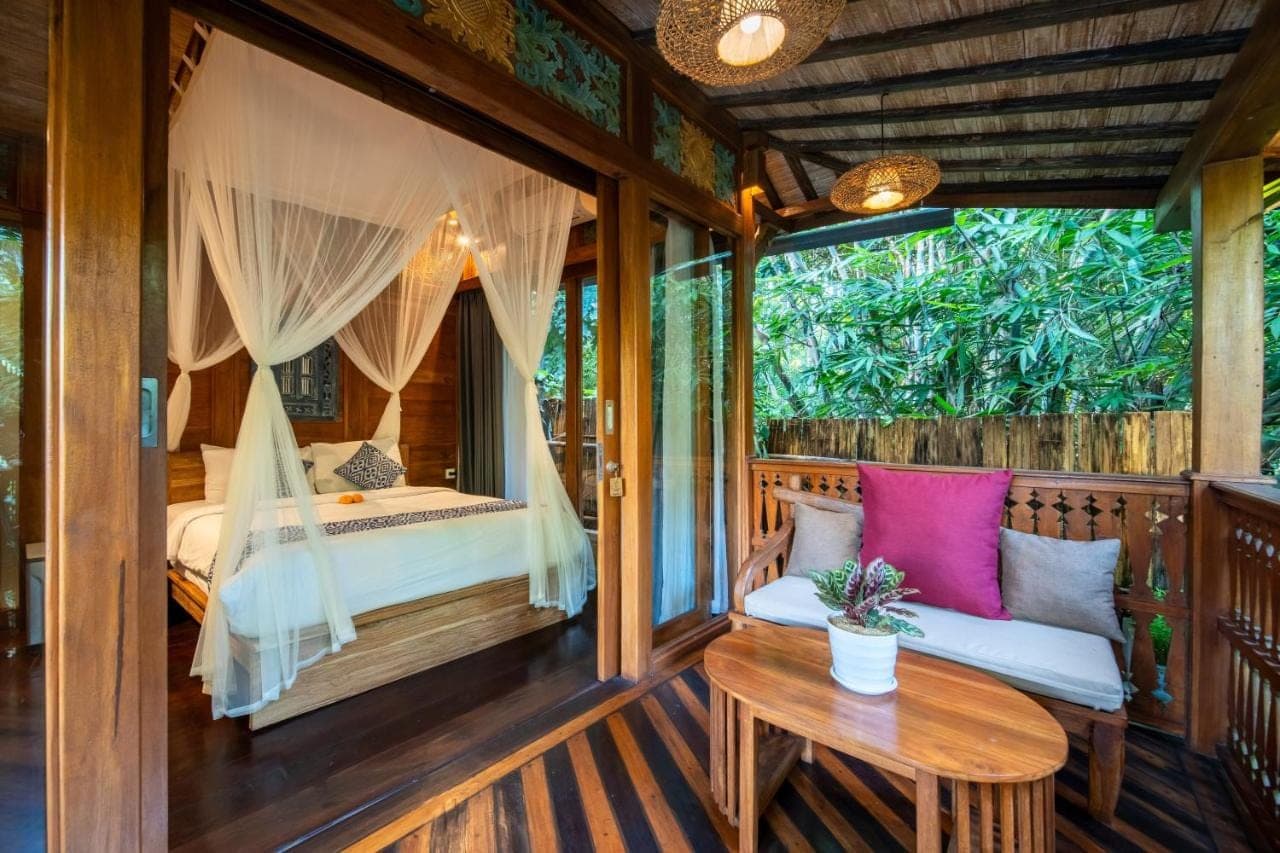 a room with a bed and a table on a porch at Parvati Retreat Villas in Ubud