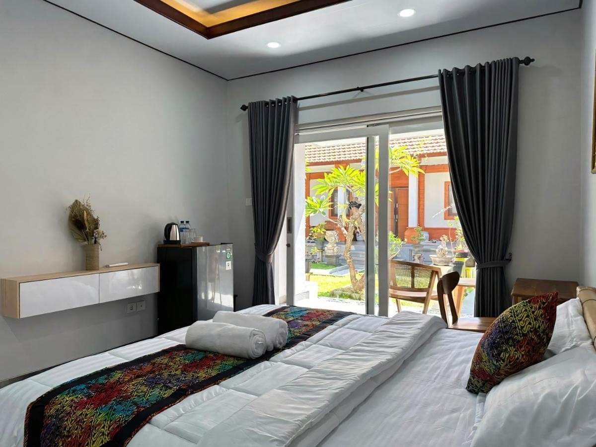 a bedroom with a large bed and a sliding glass door at suka homestay in Sanur