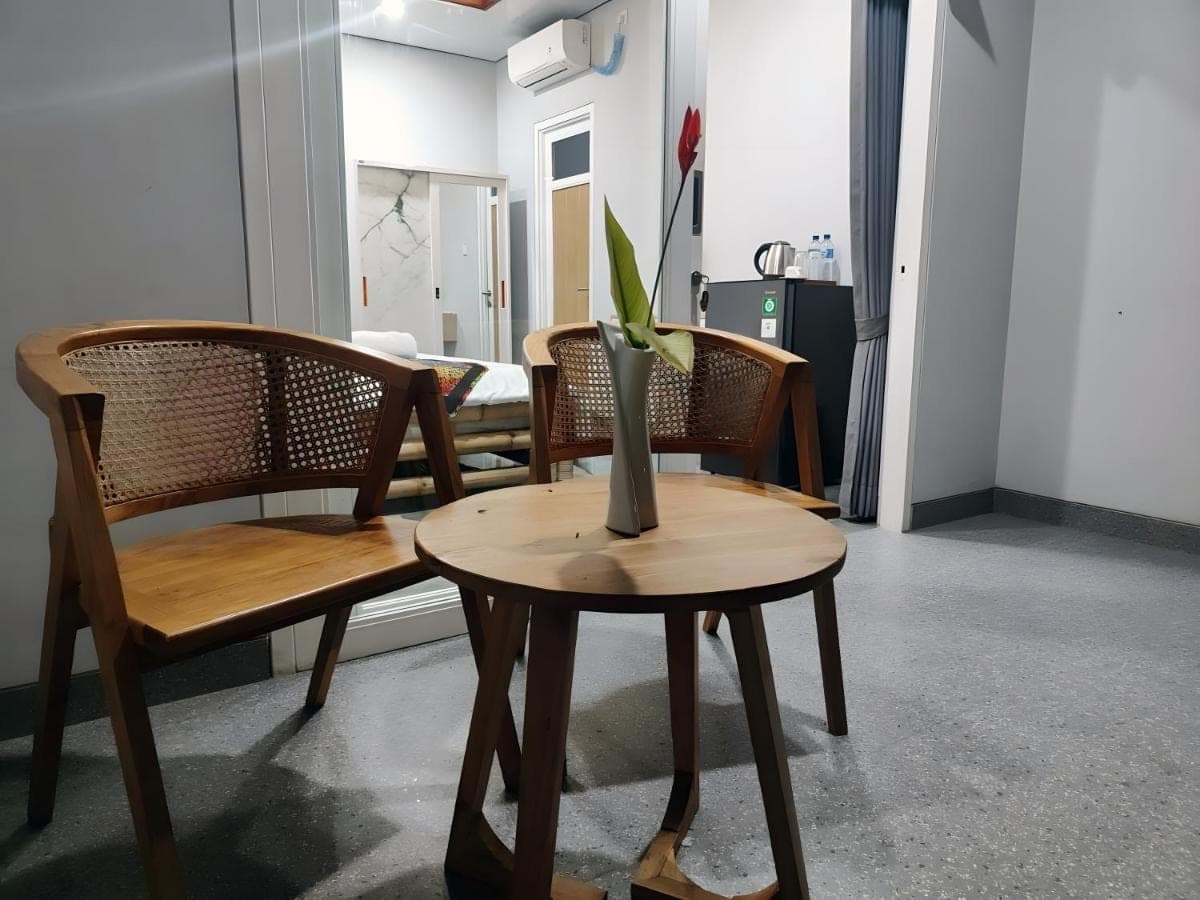 a table with two chairs and a vase on it at suka homestay in Sanur