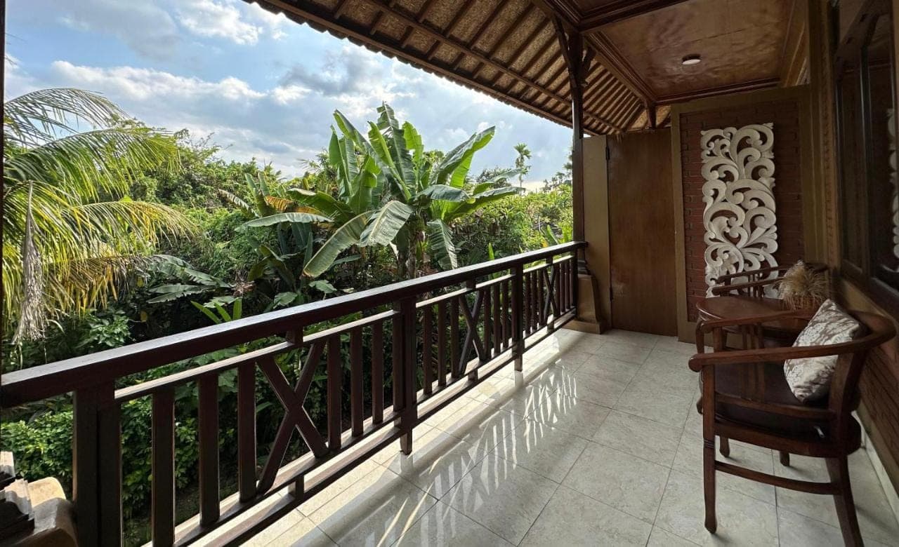 a balcony with a chair and a view of the jungle at Saren Indah Hotel in Ubud