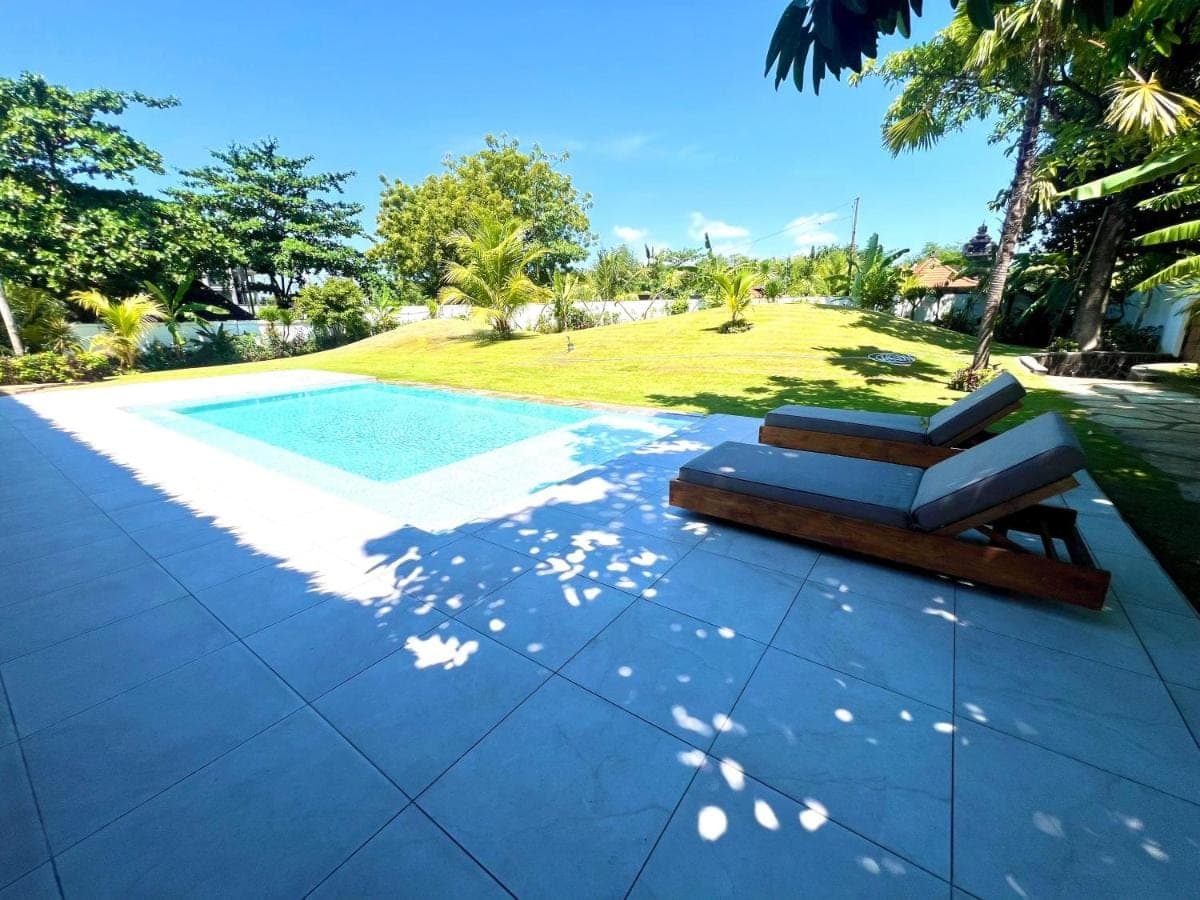 a patio with a bench next to a swimming pool at Peninsula Bay Resort in Nusa Dua