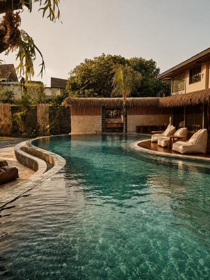 a swimming pool with blue water in front of a building at White Penny Bali in Seminyak