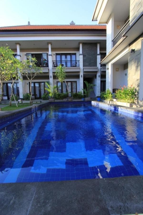 a swimming pool in front of a building at De Dukuh Guest House in Kuta