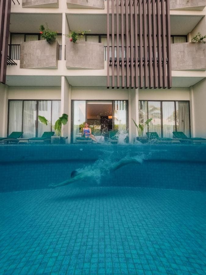 a person swimming in a swimming pool in a building at Four Points by Sheraton Bali, Seminyak in Seminyak