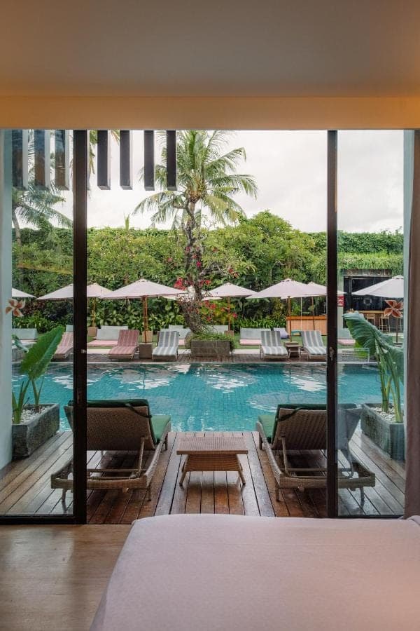 a hotel room with a pool with chairs and umbrellas at Four Points by Sheraton Bali, Seminyak in Seminyak