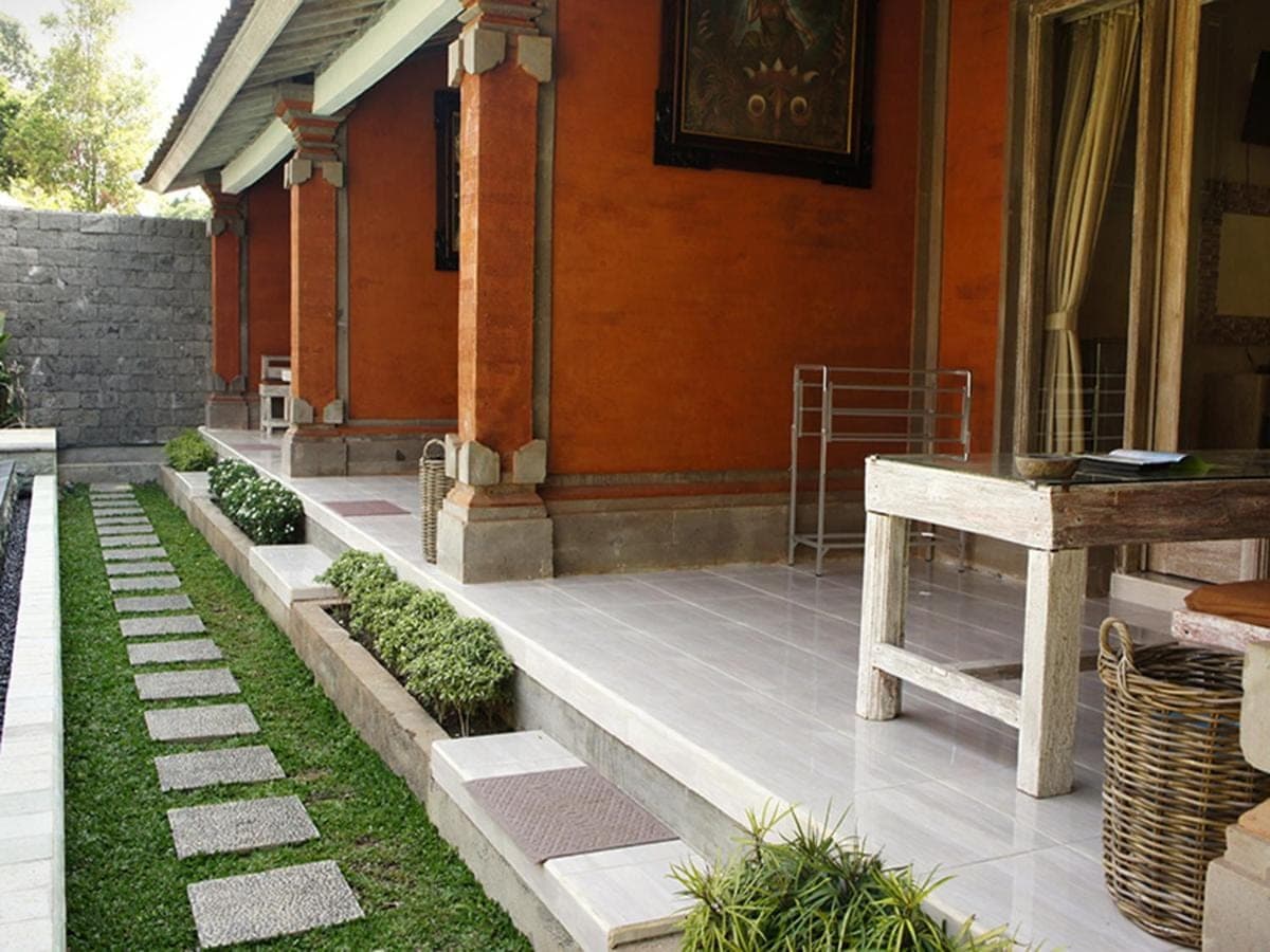 a porch of a house with a table and grass at Bale Bali Inn in Ubud