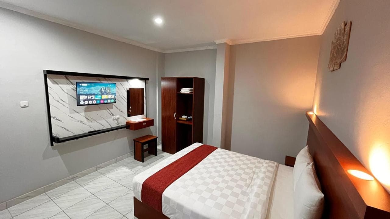 a hotel room with a bed and a flat screen tv at Dara House in Kuta