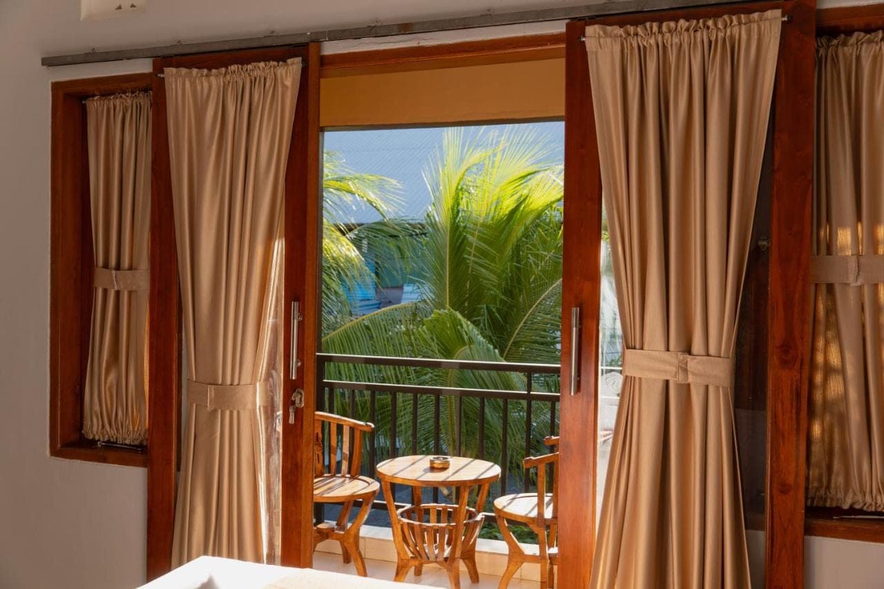 a room with a balcony with a table and a window at Dara House in Kuta