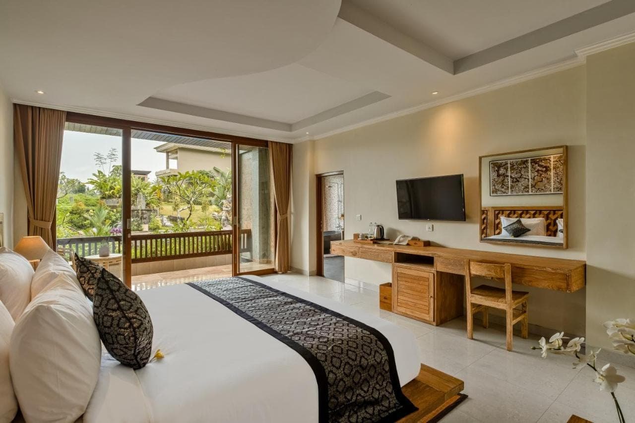 a bedroom with a white bed and a television at Gynandha Ubud Cottage in Ubud