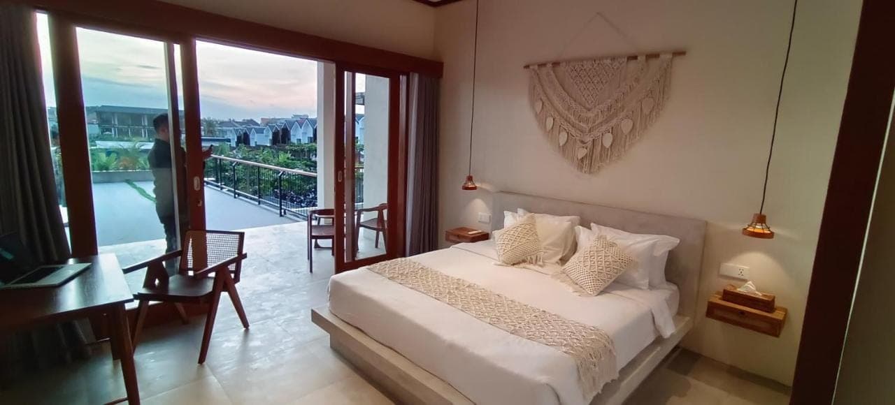 a bedroom with a bed with a view of a balcony at FULLMOON CANGGU Nelayan in Canggu