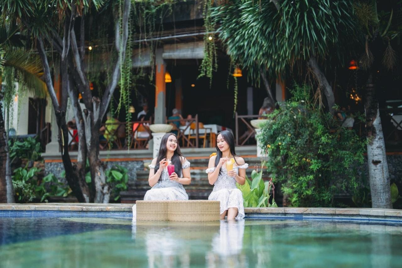 two women sitting in the water with drinks at Puri Wirata Dive Resort and Spa Amed in Amed