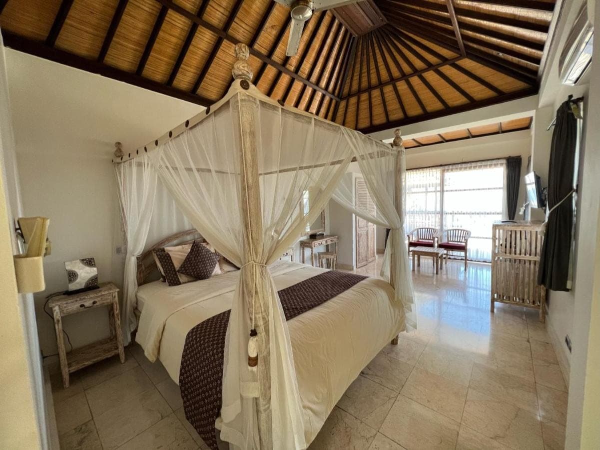 a bedroom with a large bed with a canopy at Puri Wirata Dive Resort and Spa Amed in Amed