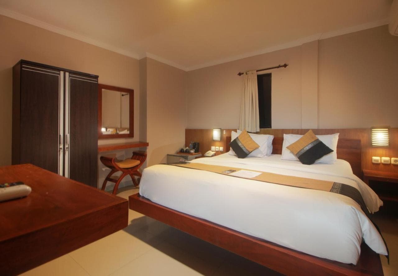 a bedroom with a large white bed and a desk at Nesa Sanur Bali in Sanur