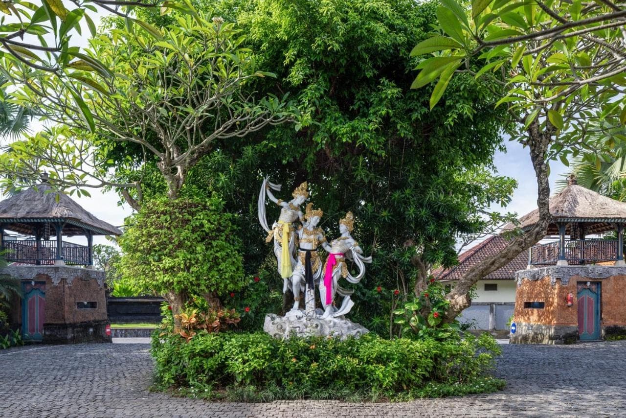 a statue of an angel sitting next to trees at The Alantara Sanur in Sanur