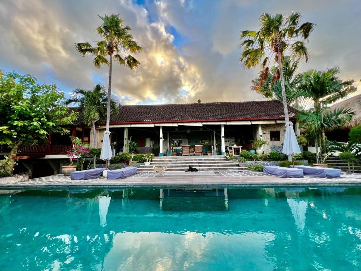 a resort with a swimming pool and palm trees at Villa Anjing in Nusa Dua