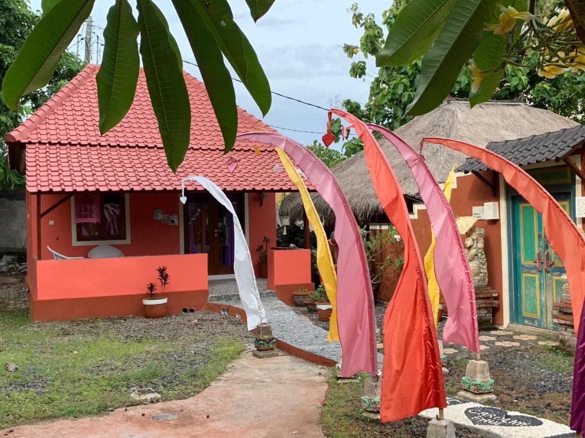 a small red house with colorful flags in front of it at Villa Anjing in Nusa Dua