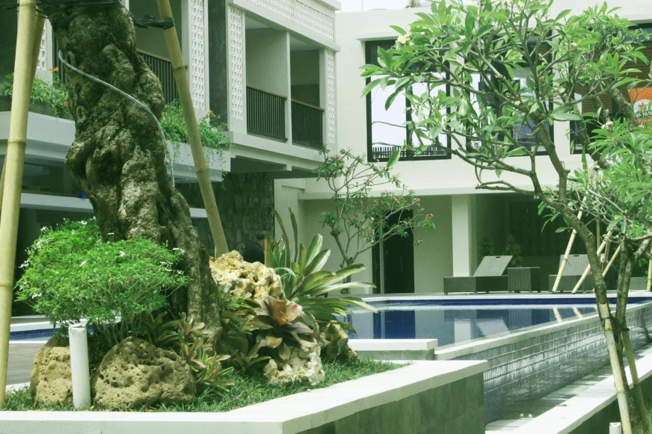 a garden in front of a building with a swimming pool at Grand Barong Resort in Kuta