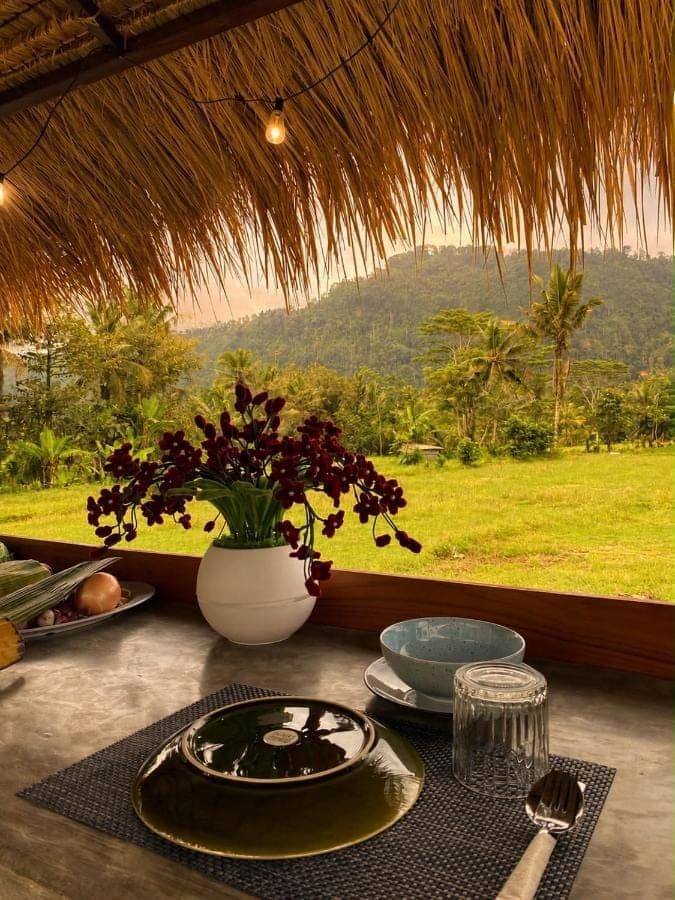 a table with a plate of food and a vase at Dewi Teduh Villa in Sidemen