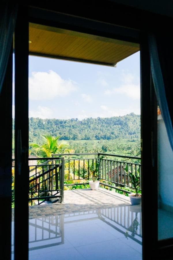 an open door to a balcony with a view at Anantalla Homestay in Sidemen