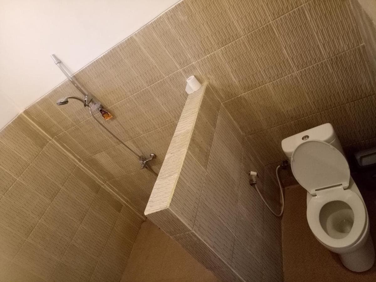 a small bathroom with a toilet and a shower at Minory Guesthouse in Amed