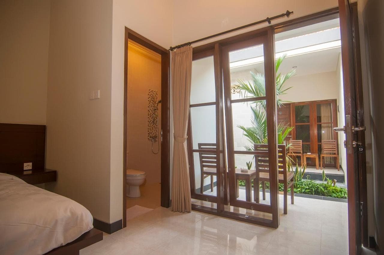 a bedroom with a bed and a balcony with a table at Duyung Homestay in Sanur