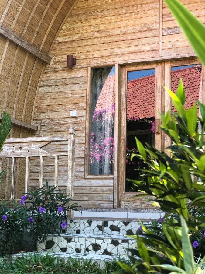 a house with a window and flowers in front of it at Lala Home Stay in Nusa Dua
