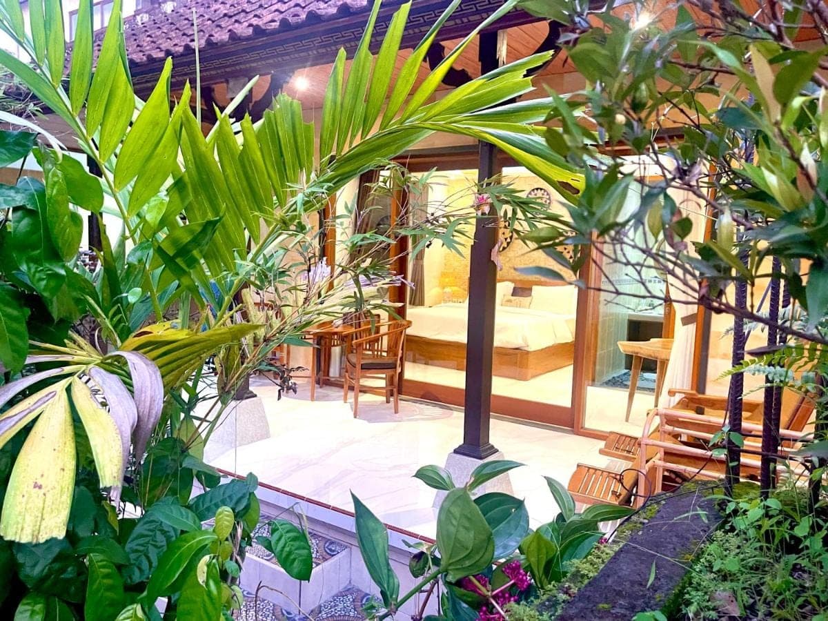 a garden with plants and a room with a couch at Ayu Homestay in Ubud