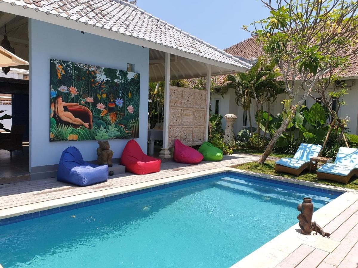 a swimming pool with colorful chairs next to a house at Starling villas in Sanur