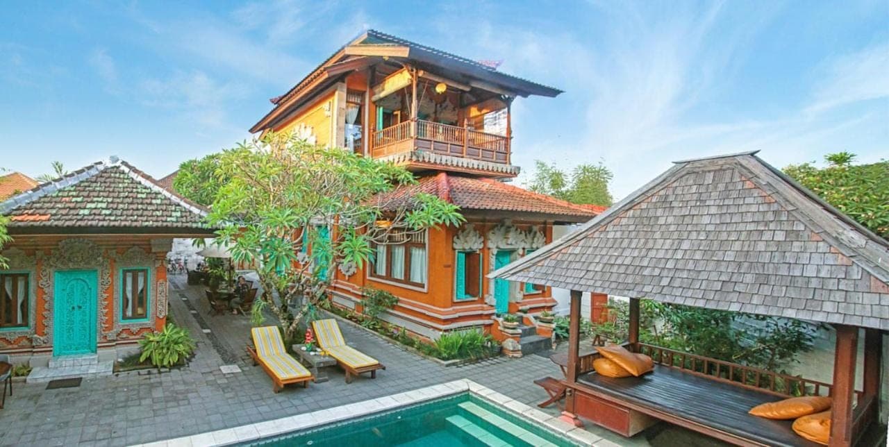 a house with a swimming pool in front of a house at Sunhouse Guesthouse in Sanur