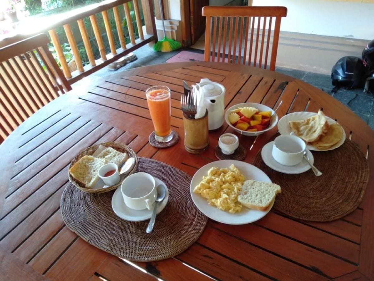 a wooden table with breakfast foods and drinks on it at Le Jardin in Amed