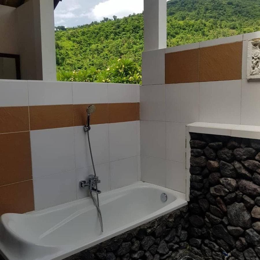 a bathroom with a bath tub with a window at Meditasi Bungalows &amp; Villas in Amed