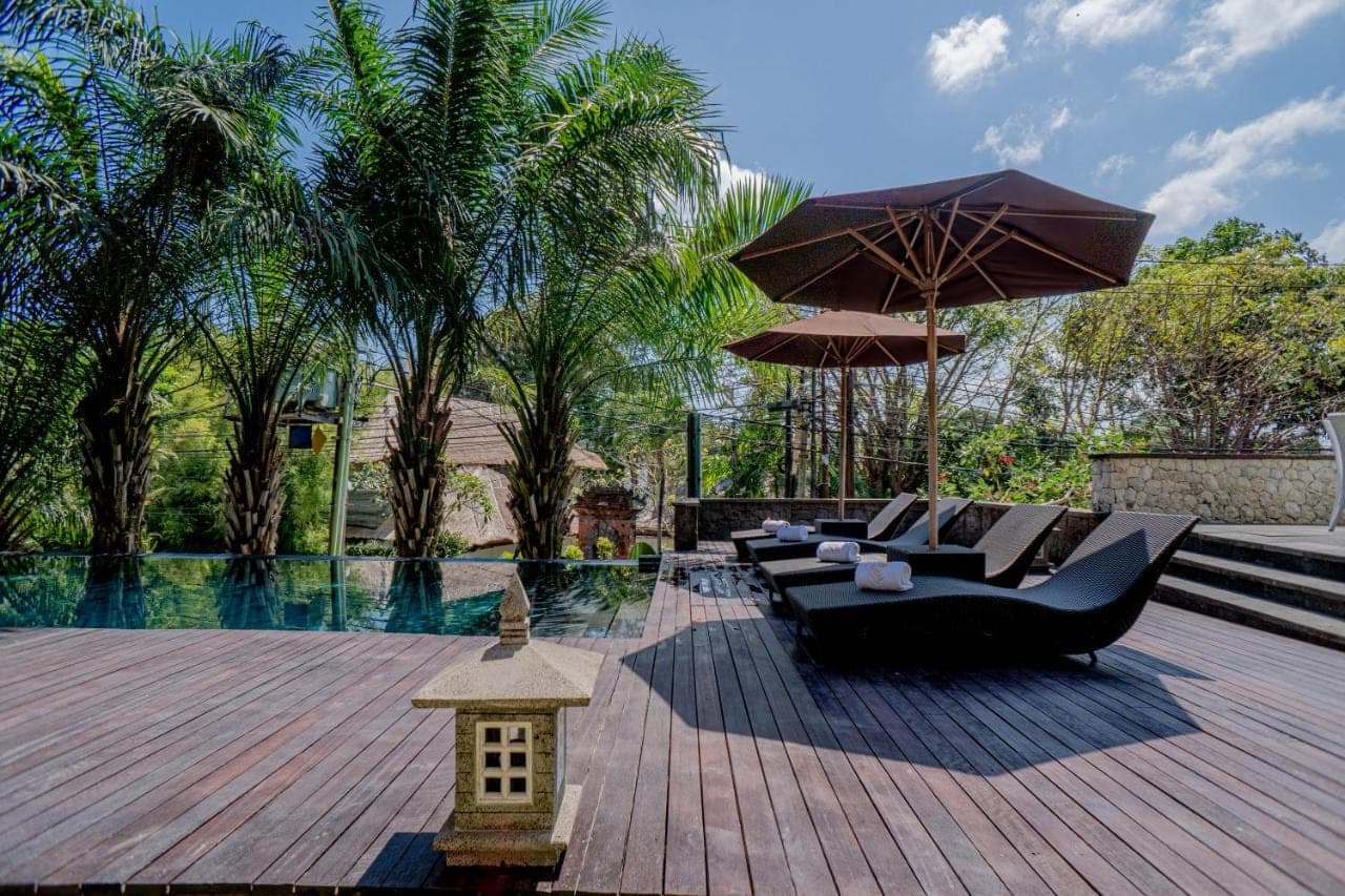 a patio with a black couch and an umbrella at djabu Echo Beach Hotel in Canggu