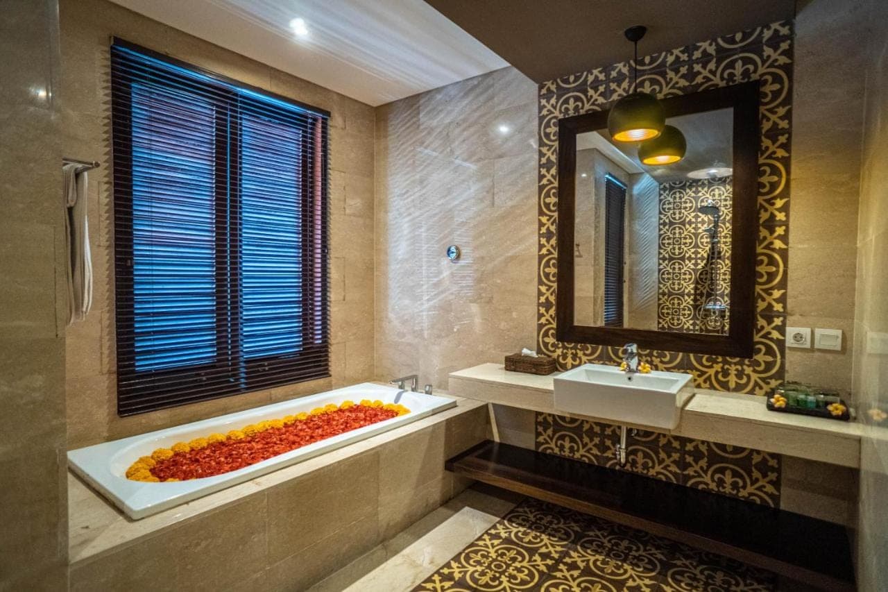 a bathroom with a tub and a sink and a mirror at djabu Echo Beach Hotel in Canggu
