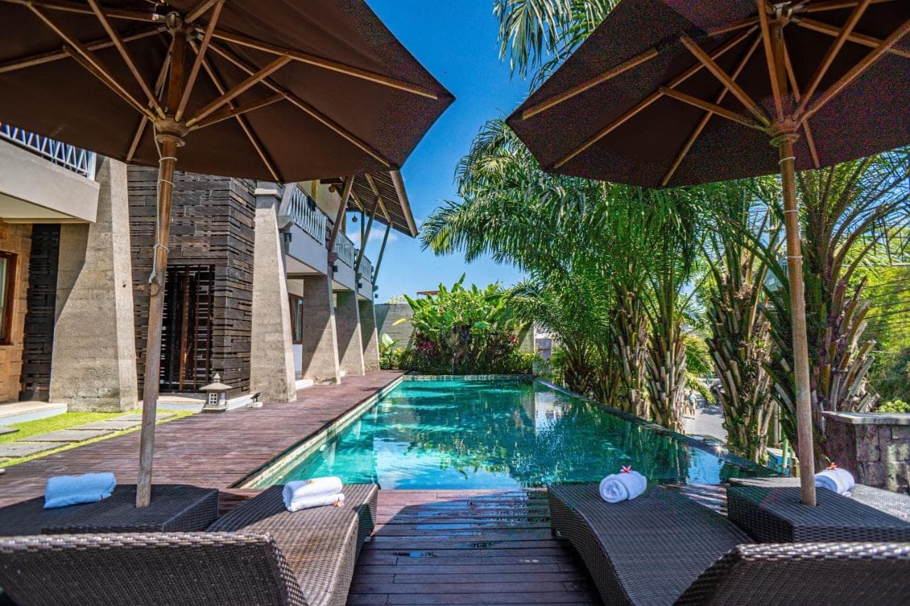 a swimming pool with two chairs and umbrellas at djabu Echo Beach Hotel in Canggu
