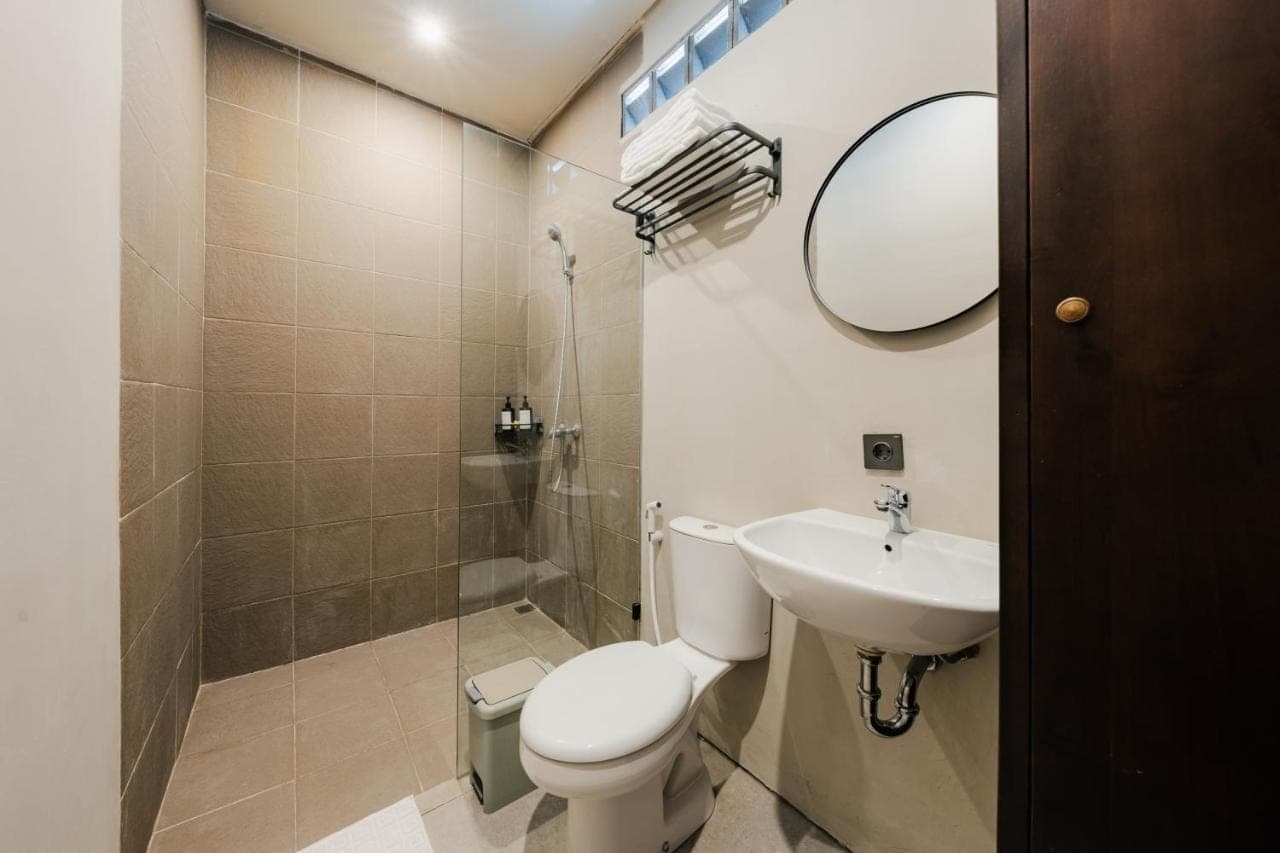 a bathroom with a toilet and a sink and a shower at Kuma House in Ubud