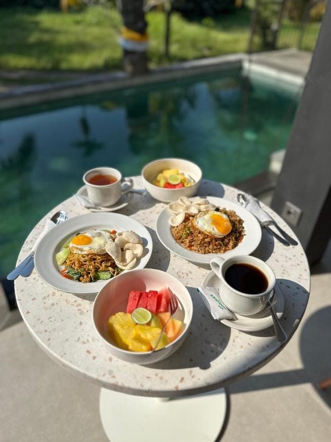a tray of food on a table with cups of coffee at Kuma House in Ubud