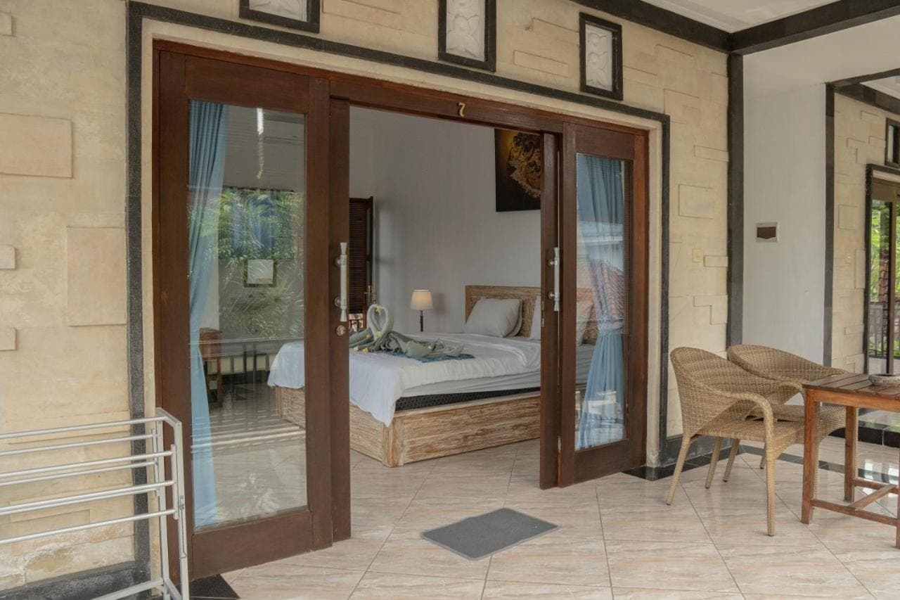 a bedroom with a bed and a glass door at Pakel's Bali Villas in Amed