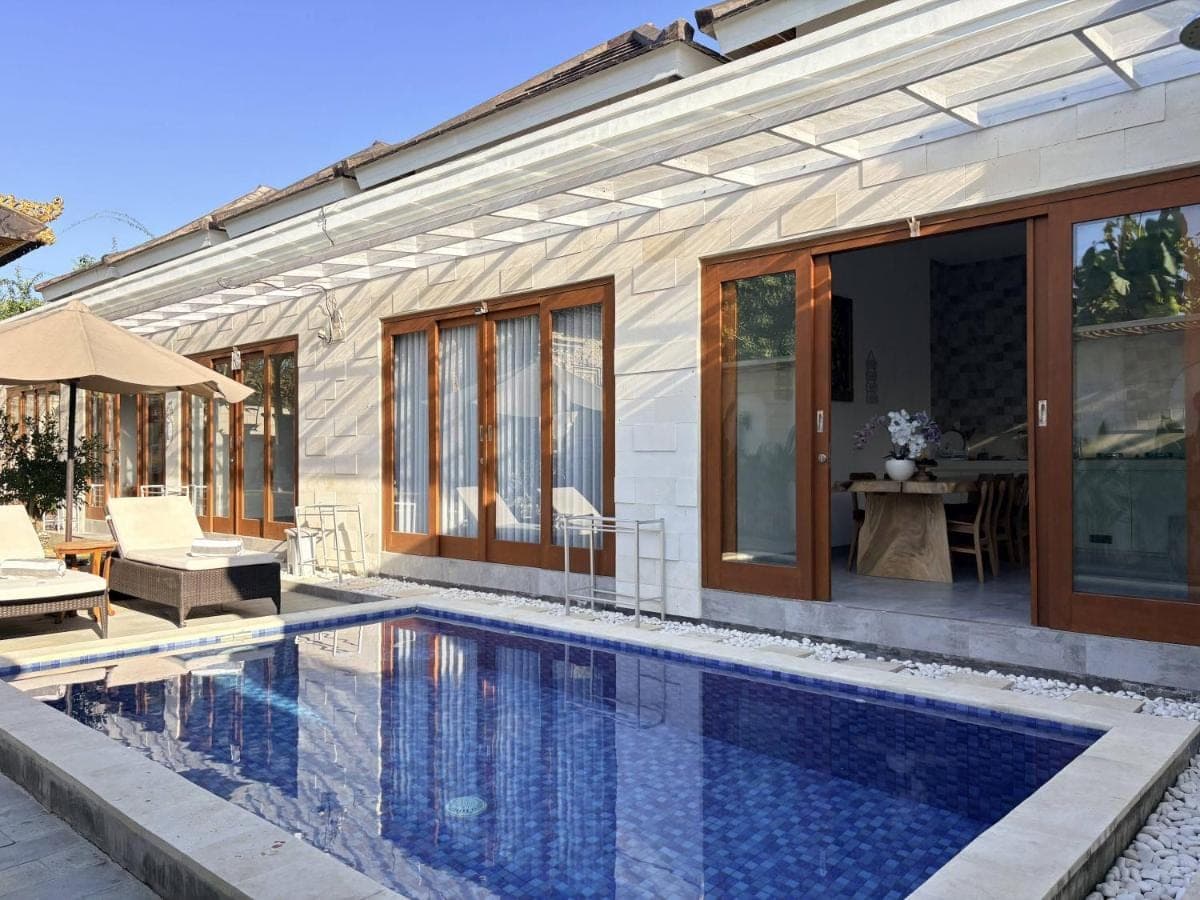 a swimming pool in front of a house at Amy Guesthouse Nusa Dua in Nusa Dua