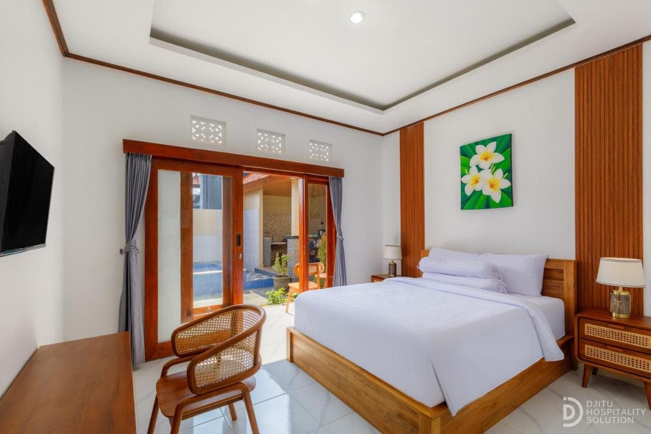 a bedroom with a bed and a tv and a chair at Pradja Homestay in Nusa Dua