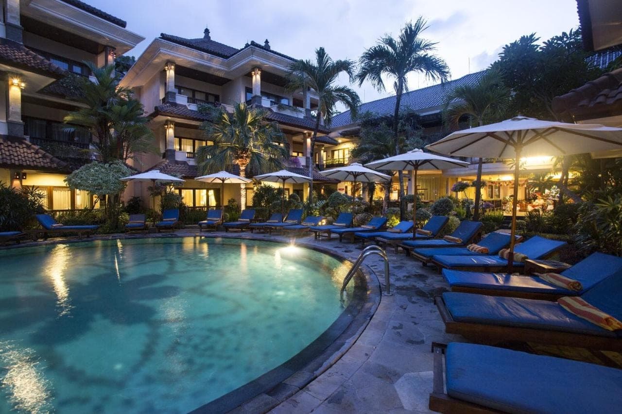 a hotel with a swimming pool with chairs and umbrellas at Parigata Resorts and Spa in Sanur