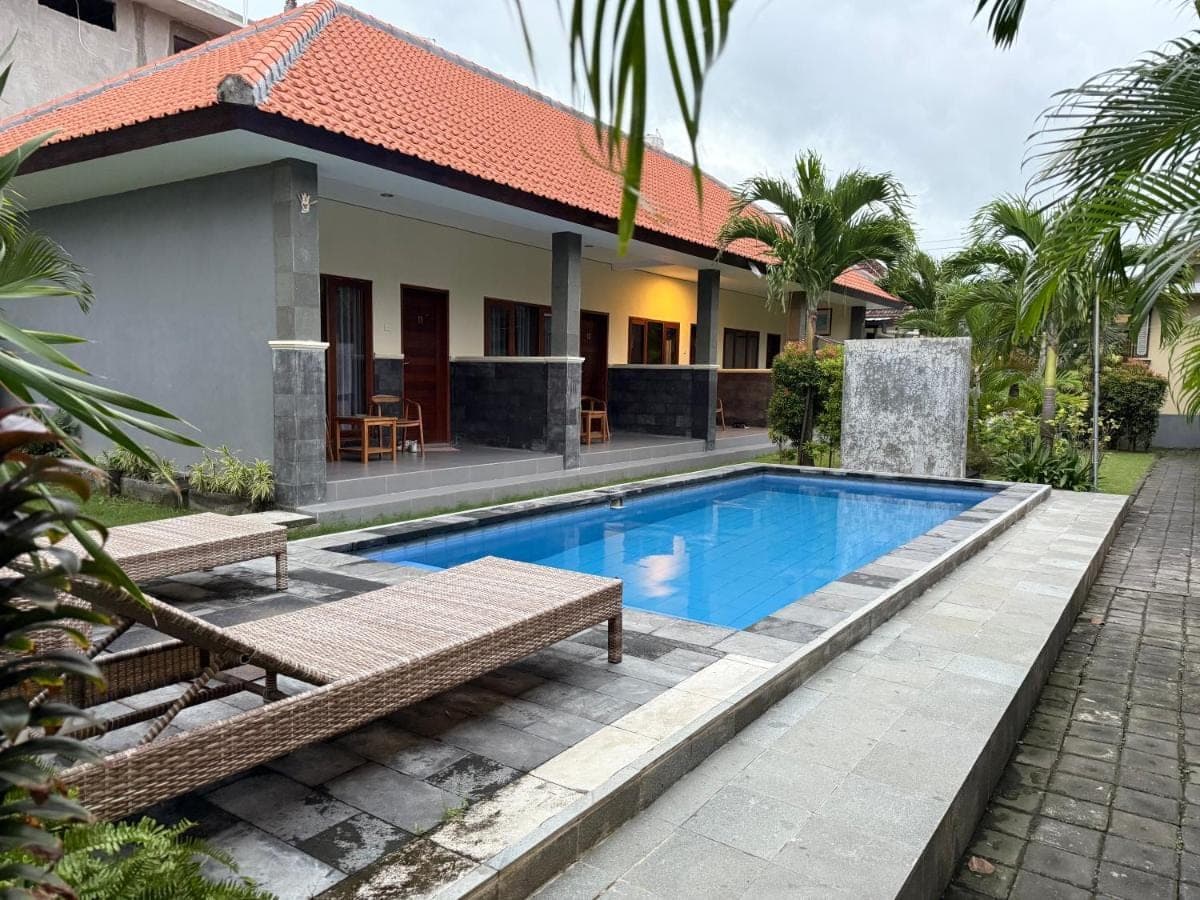 a villa with a swimming pool in front of a house at Dega Gardens in Canggu