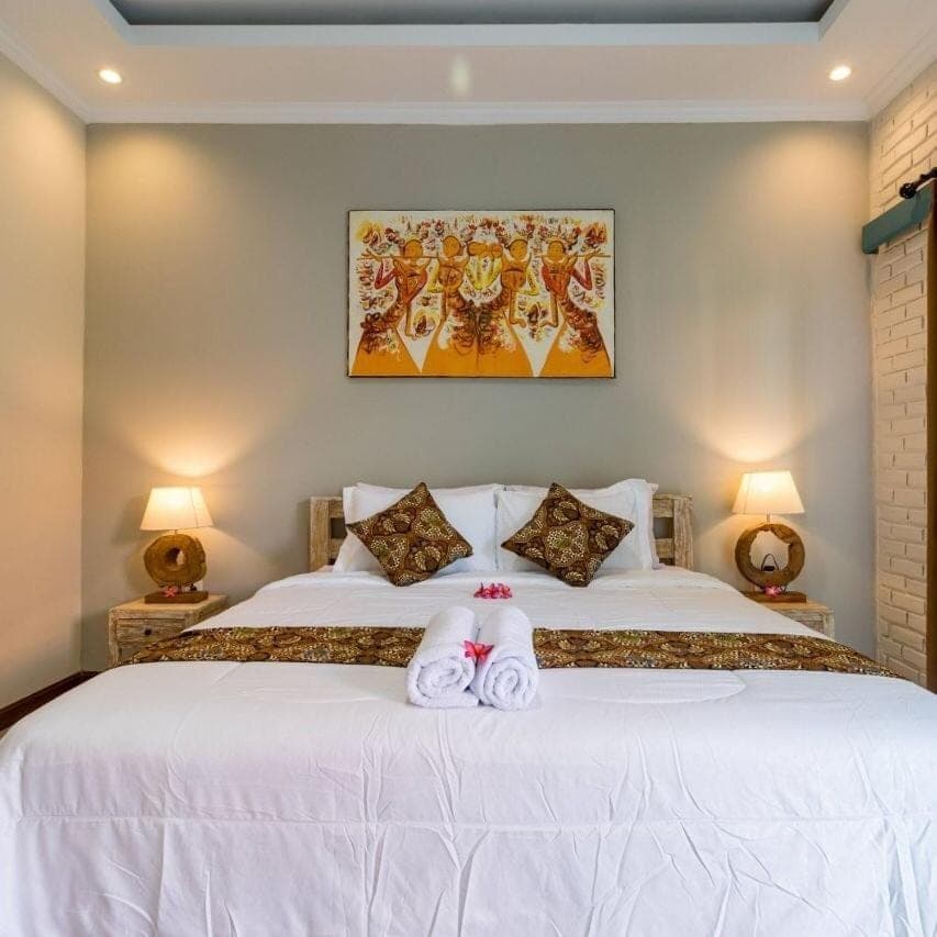 a bedroom with a white bed with two stuffed animals on it at D Anyar Stay and Surf in Canggu
