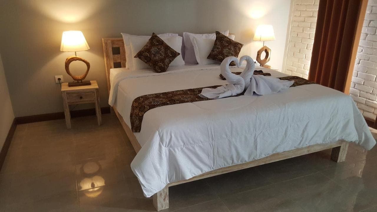 two swans sitting on a bed in a bedroom at D Anyar Stay and Surf in Canggu